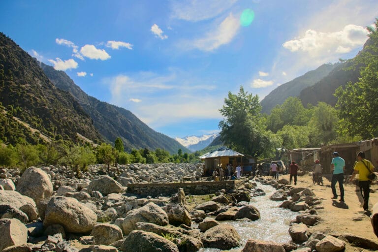 Valle de Kalash en el distrito de Chitral, Pakistán, rodeado de montañas y un riachuelo de piedras